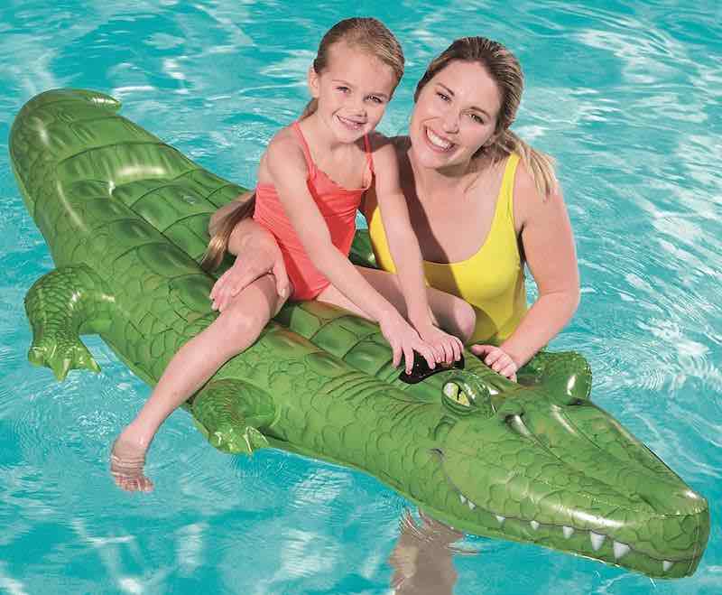 Mutter-mit-Kind-auf-aufblasbarem-Krokodil-in-Pool